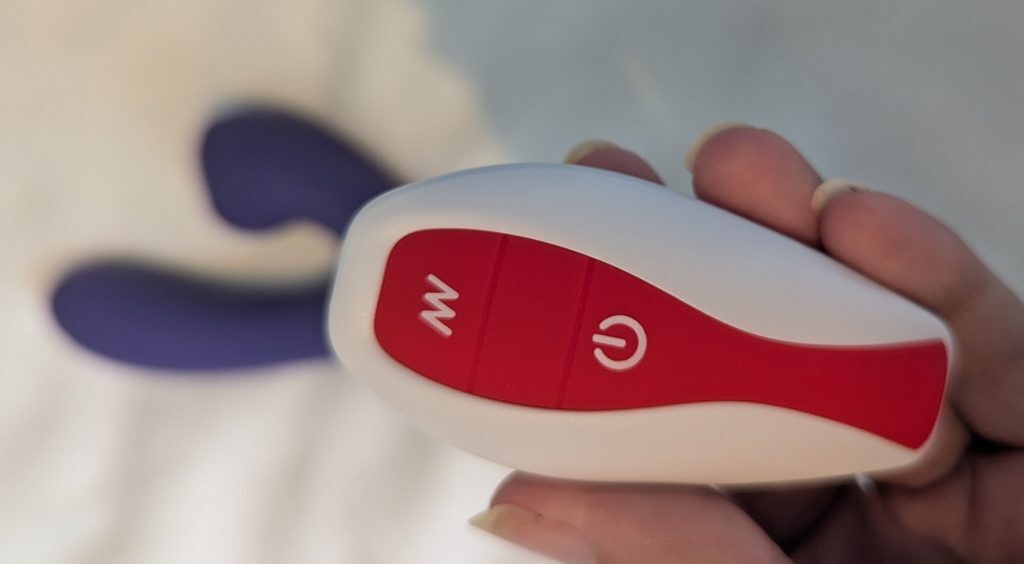 remote control of huxi sucking sweet in hand with purple dual stimulator in background